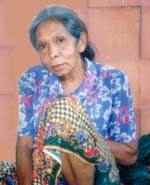 A petite Thai woman resting in traditional Thai-style on a bench in front of a house in Bangkok